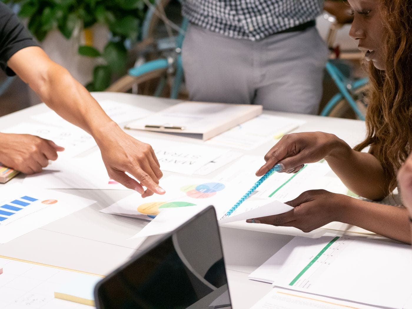 Plusieurs mains disposent des graphiques et des documents sur une table de travail.